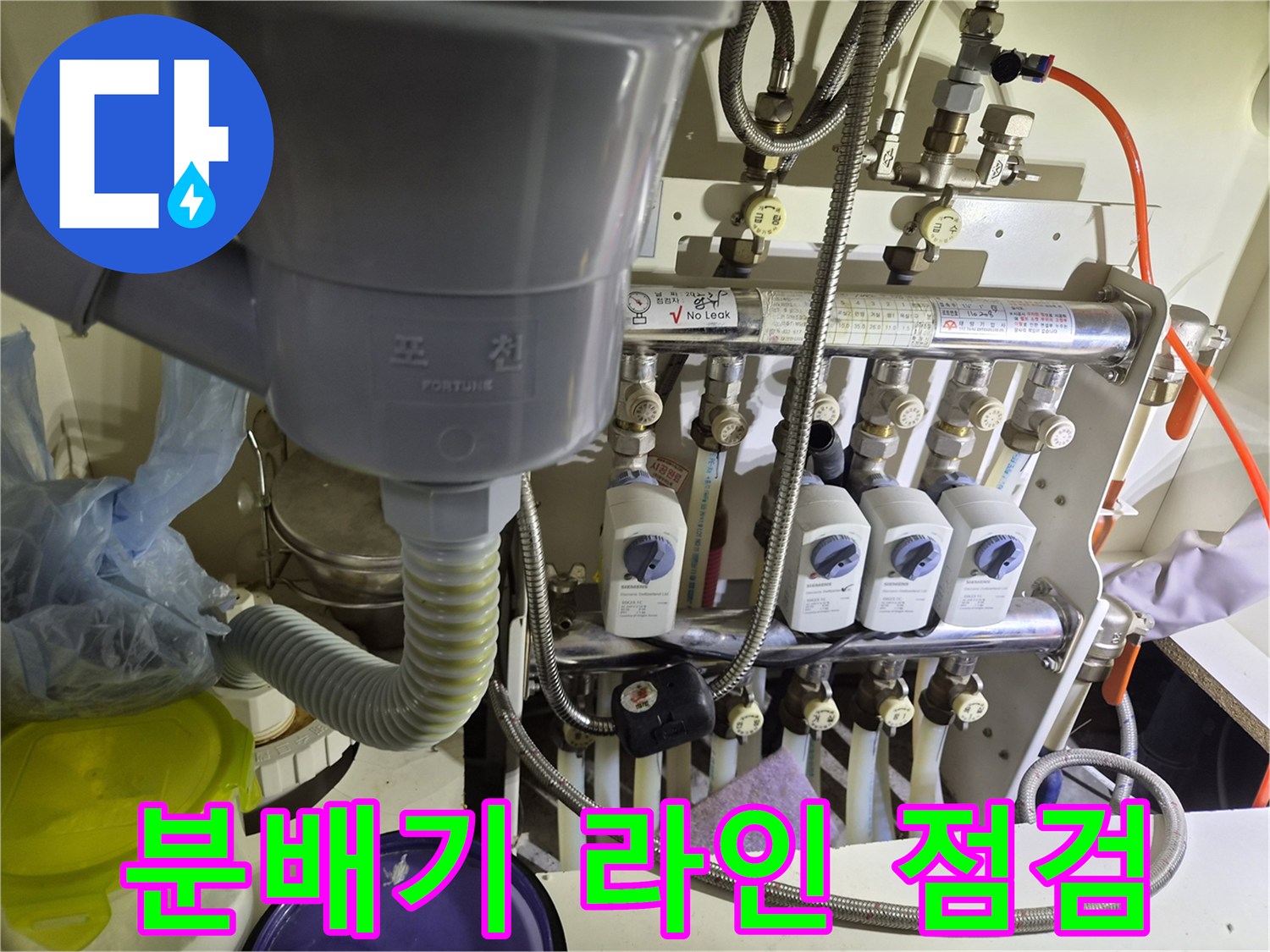 싱크대 아래 복잡하게 얽힌 분배기 및 배관 연결부 전체 전경
