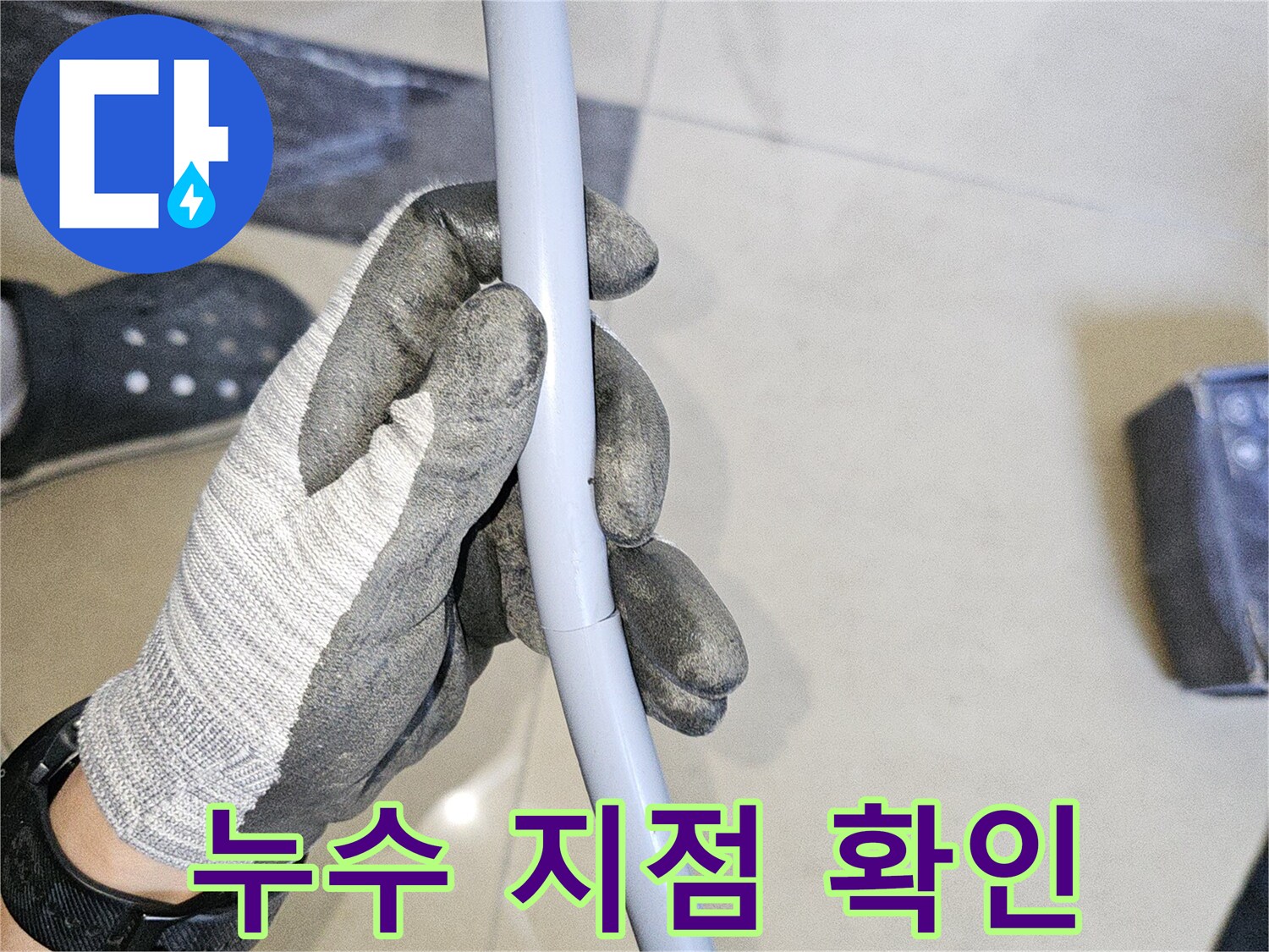 장갑을 낀 작업자가 파손된 것으로 의심되는 회색 배관을 잡고 있는 장면