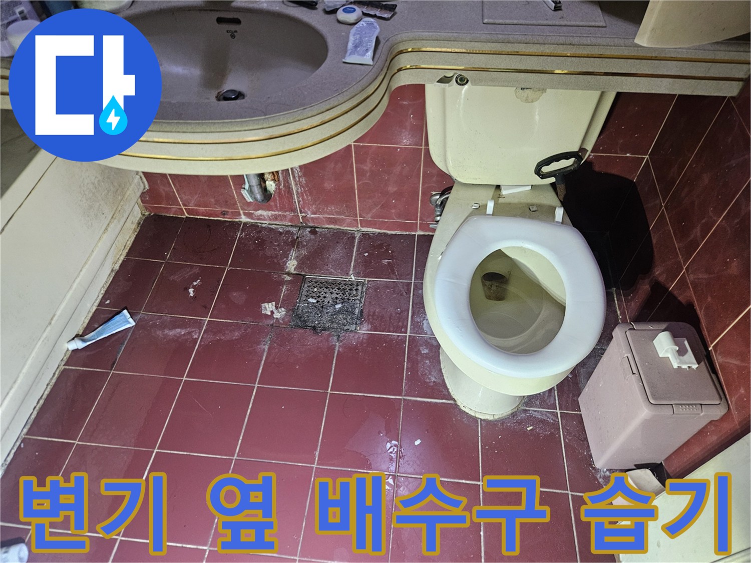 변기와 세면대 사이 배수구 주변의 타일 변색 및 습기 현상 사진입니다.