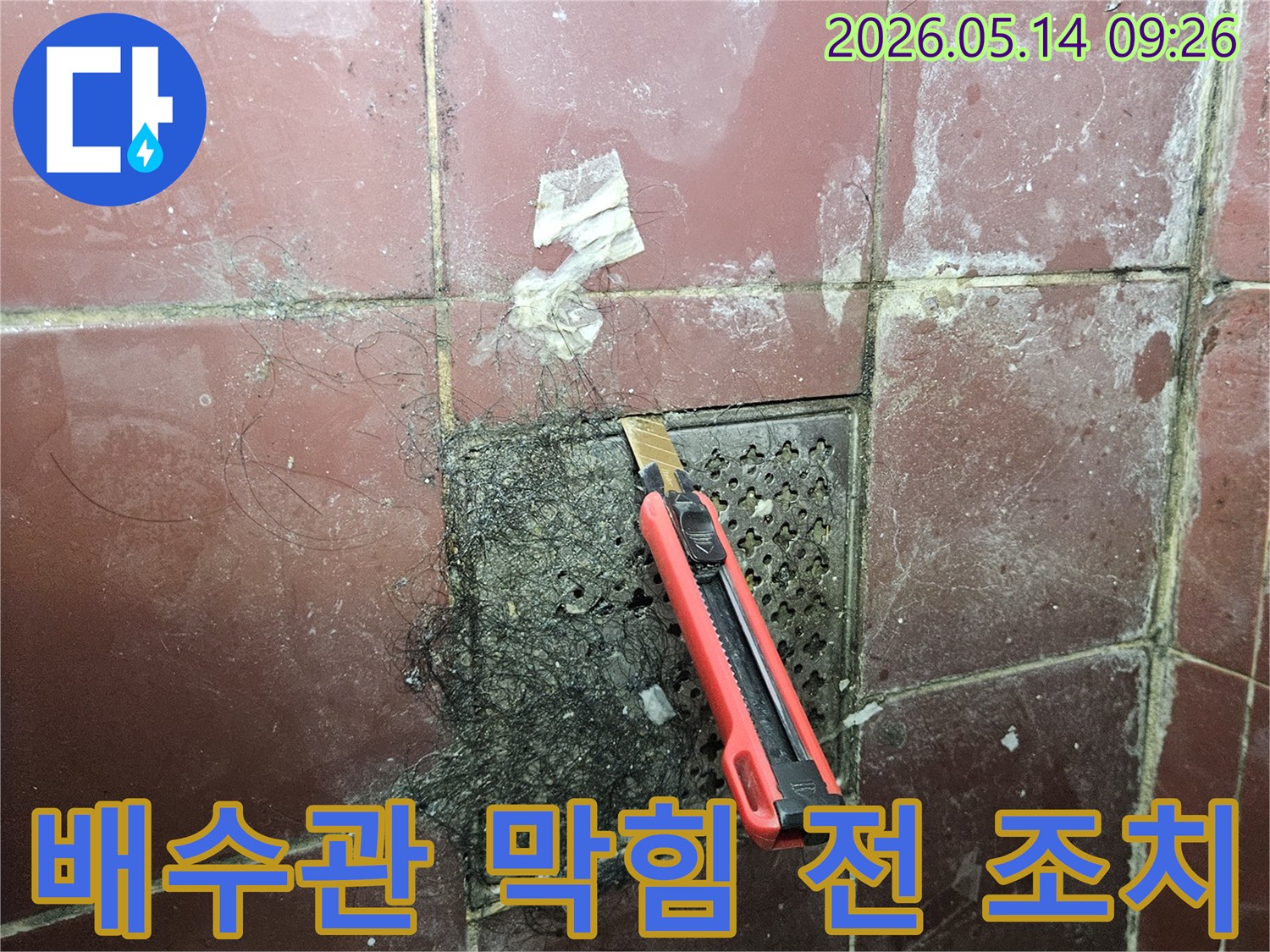 오래된 욕실 배수구에 엉킨 머리카락과 슬러지를 커터칼로 긁어내며 누수 발생 전 조치를 하는 모습