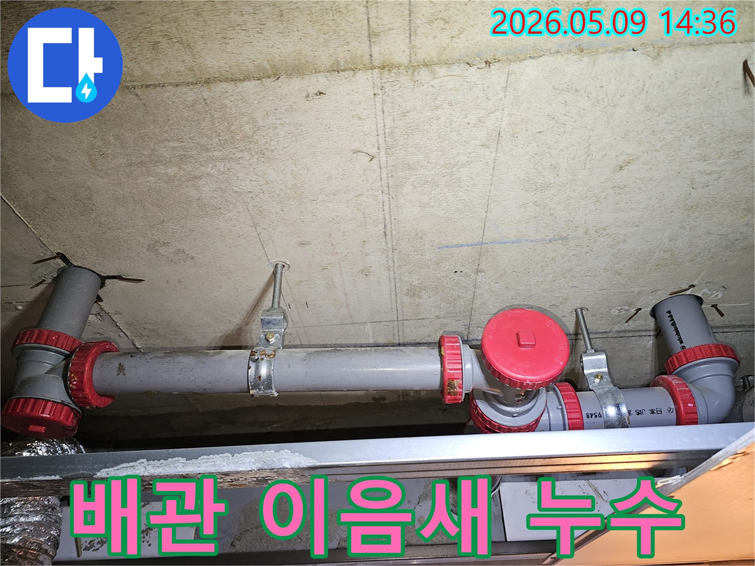 천장 배관의 붉은색 이음새 부분에서-누수가 발생할 수 있어-전문가가 꼼꼼히 점검합니다