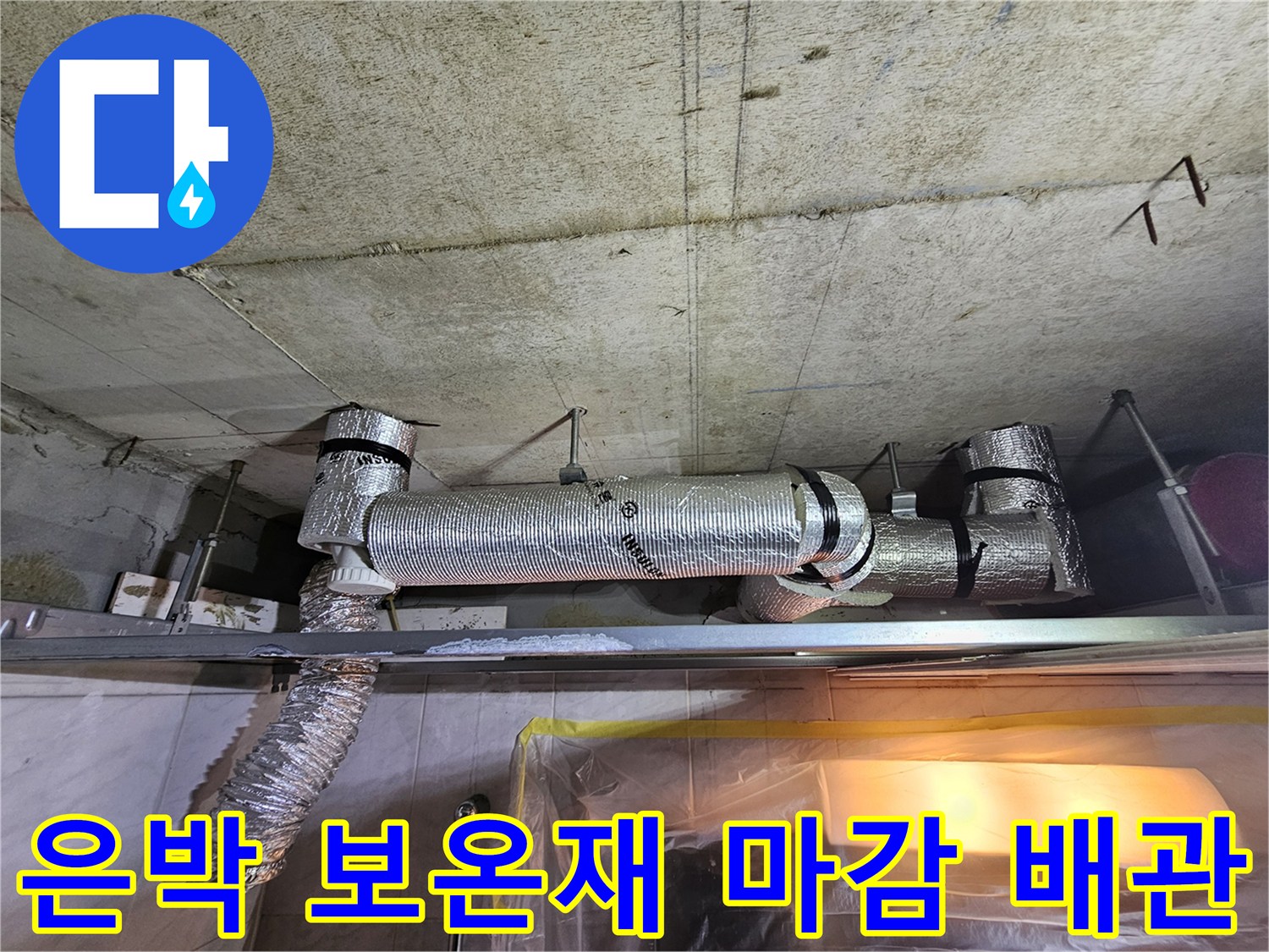 천장에 설치된 은박 단열재로 감싸진 하수 배관의 모습
