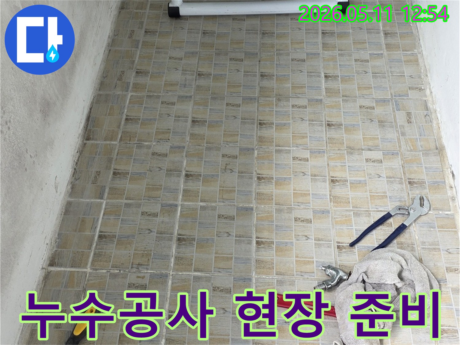 누수 공사 현장에서-타일 벽면을 배경으로-작업 도구들이 가지런히 놓여있는 모습