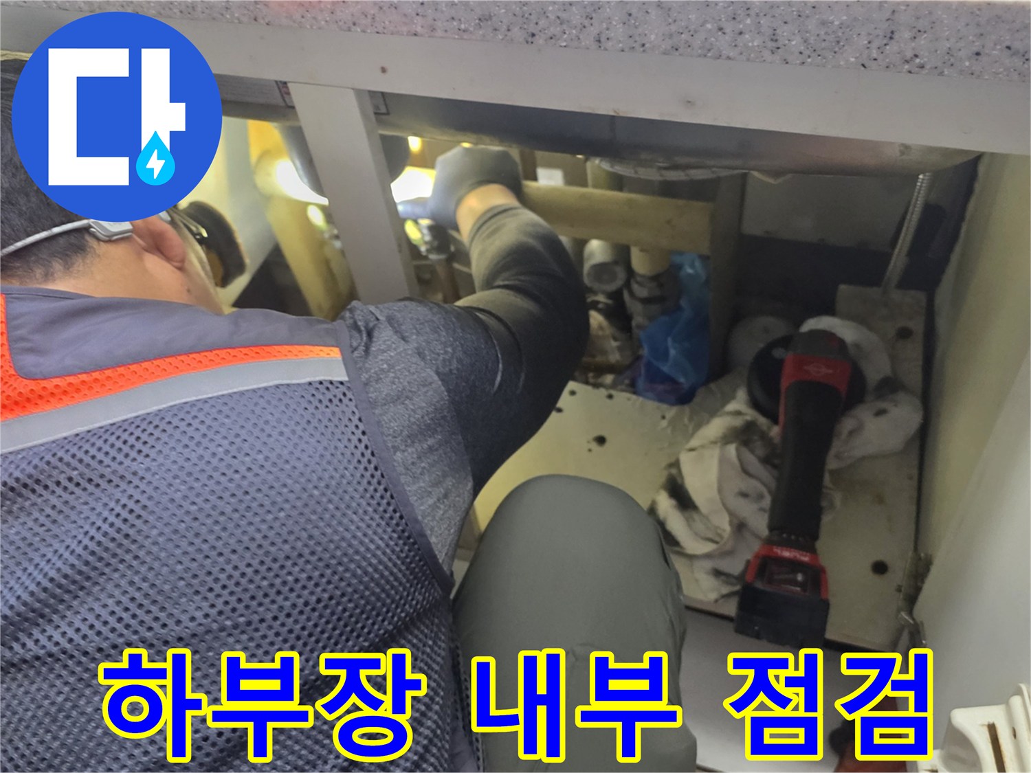 싱크대 아래 좁은 공간에서 분배기 누수를 찾는 작업 모습