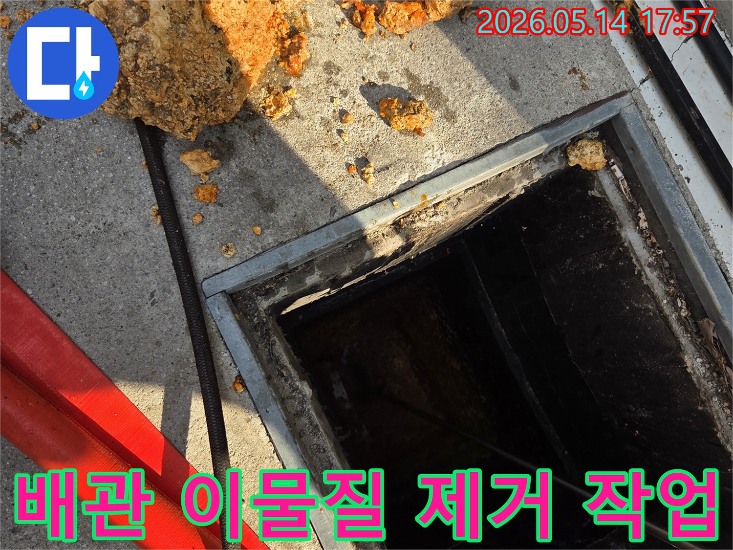 콘크리트-바닥에-열린-배관-점검구와-그-주변에-쌓인-오래된-이물질-덩어리-배관-청소-작업-모습