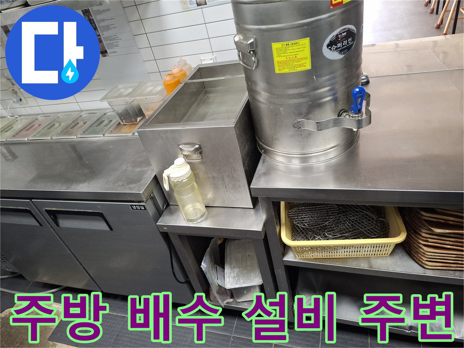 조리대 하단 스테인리스 수납장과 배수 트렌치 인근 모습입니다.