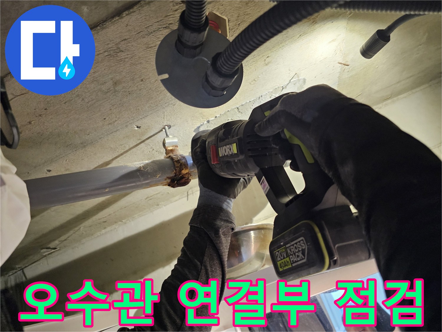 화장실 천장 내부의 오수관 연결 부위와 전동 공구 작업 모습