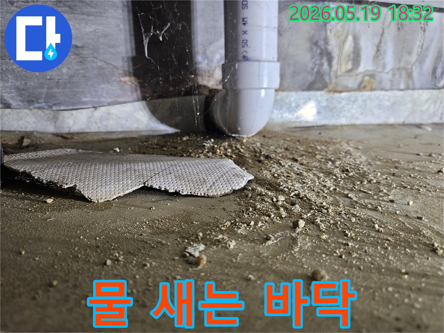 콘크리트 바닥에 물과 흙이 섞여-배관 주변에서 발생한 누수 상황을 보여줍니다