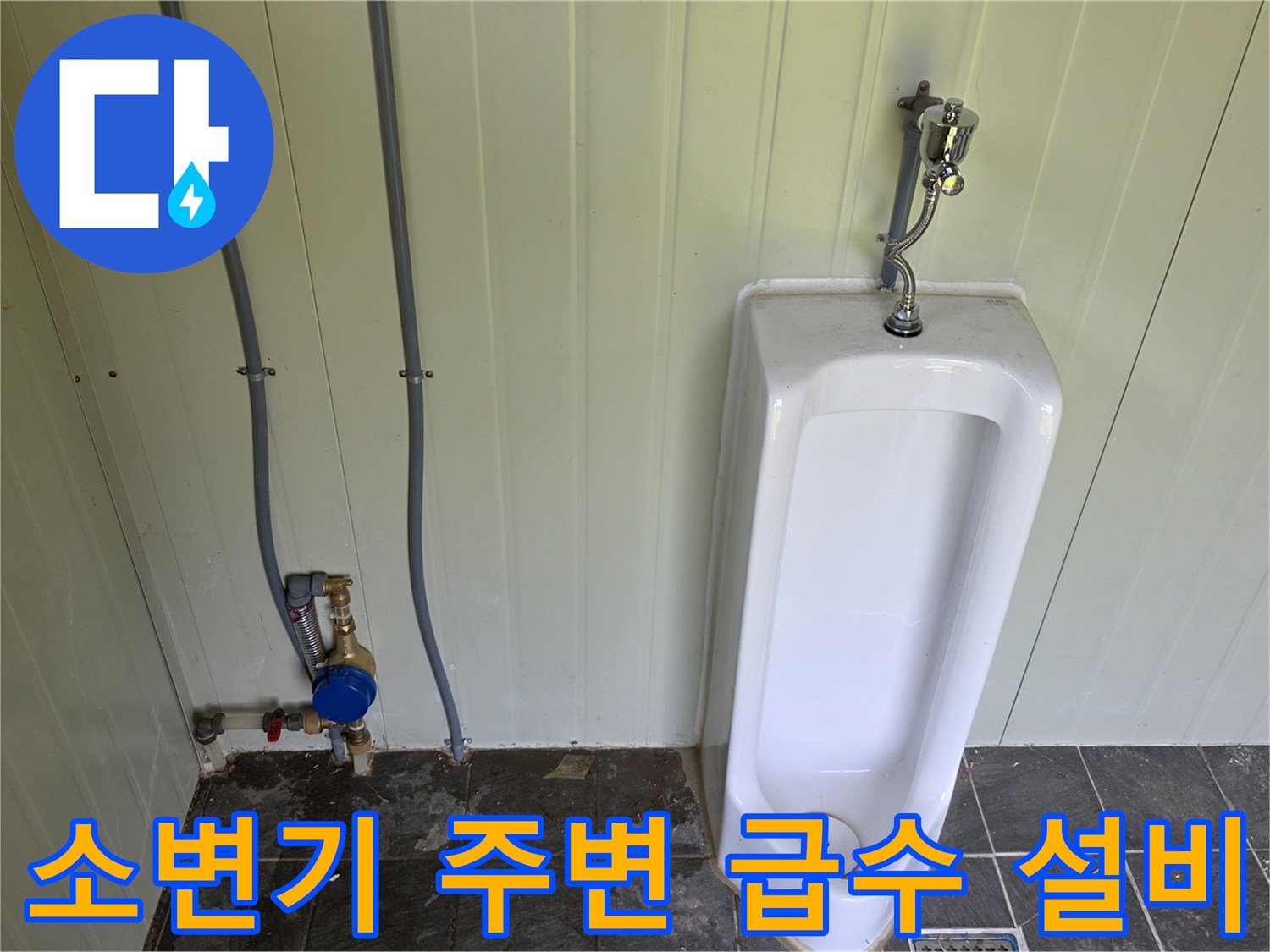 소변기 측면에 설치된 수도 계량기와 은색 배관