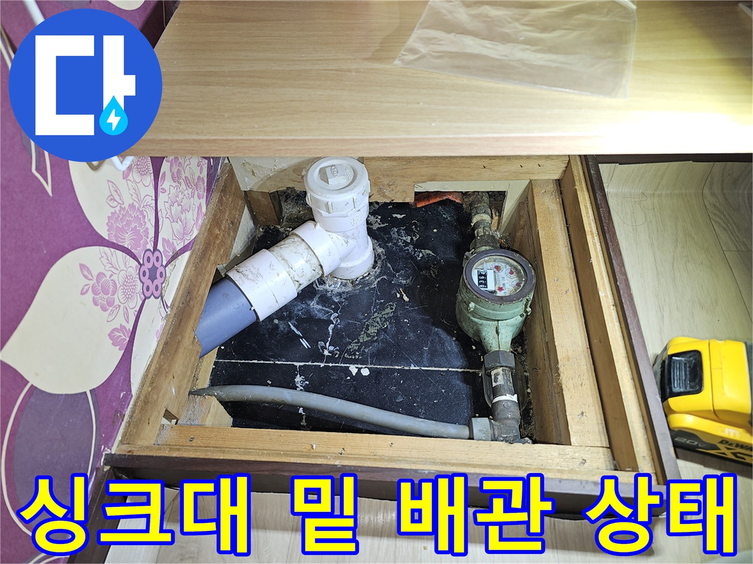 상가 하부장 내부의 수도 계량기와 노후된 배관 연결 부위