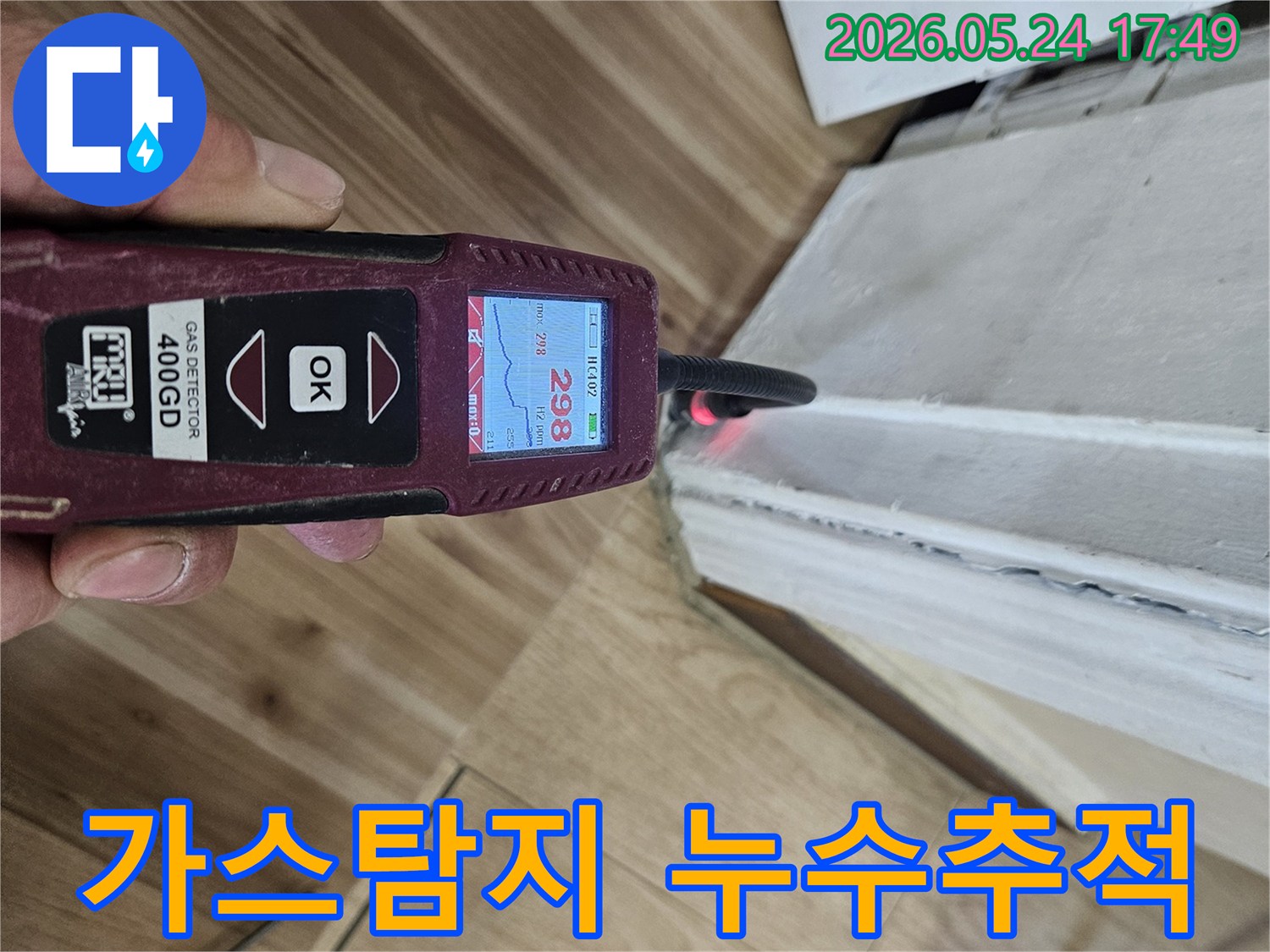 누수 엔지니어가 가스 탐지 장비를 사용하여 벽면 하단에서 누수 반응을 면밀히 확인하고 있습니다.