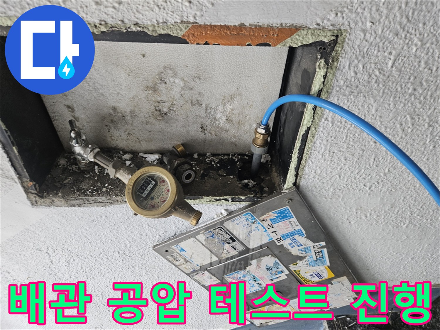 수도 계량기에 연결된 파란색 압력 측정 호스 사진입니다.