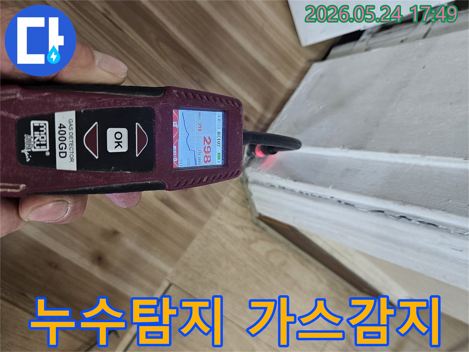 숙련된 누수 엔지니어가 가스 탐지기를 사용하여 벽과 바닥의 경계면에서 누수 반응을 확인하고 있습니다.