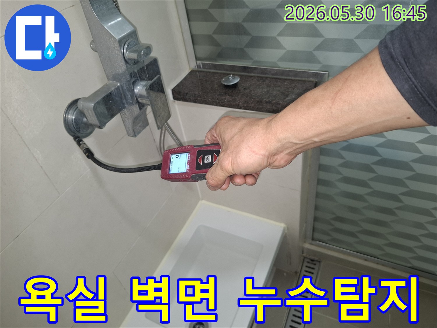 전문 엔지니어가-욕실 벽면에서-누수탐지기를-사용하여-숨겨진-누수-지점을-찾는-모습