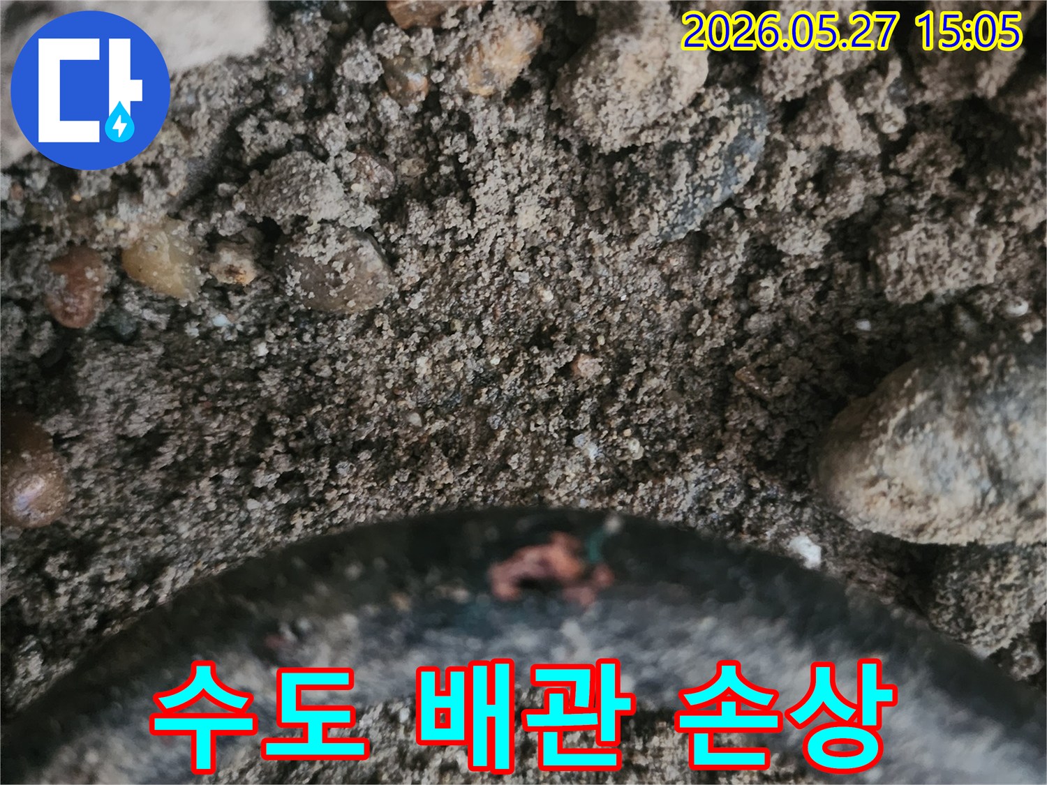 흙 속에 묻힌 수도 배관의 손상된 부위에서 누수가 발생하는 현장을 찍은 사진