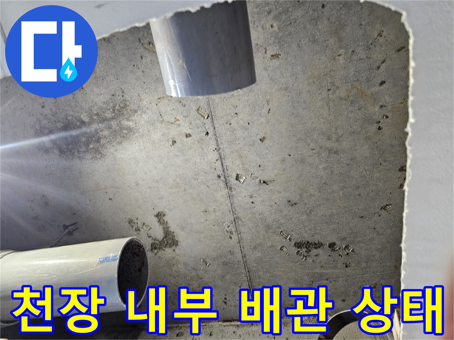 절개된 천장 공간 내부에 보이는 배관과 젖은 콘크리트 표면