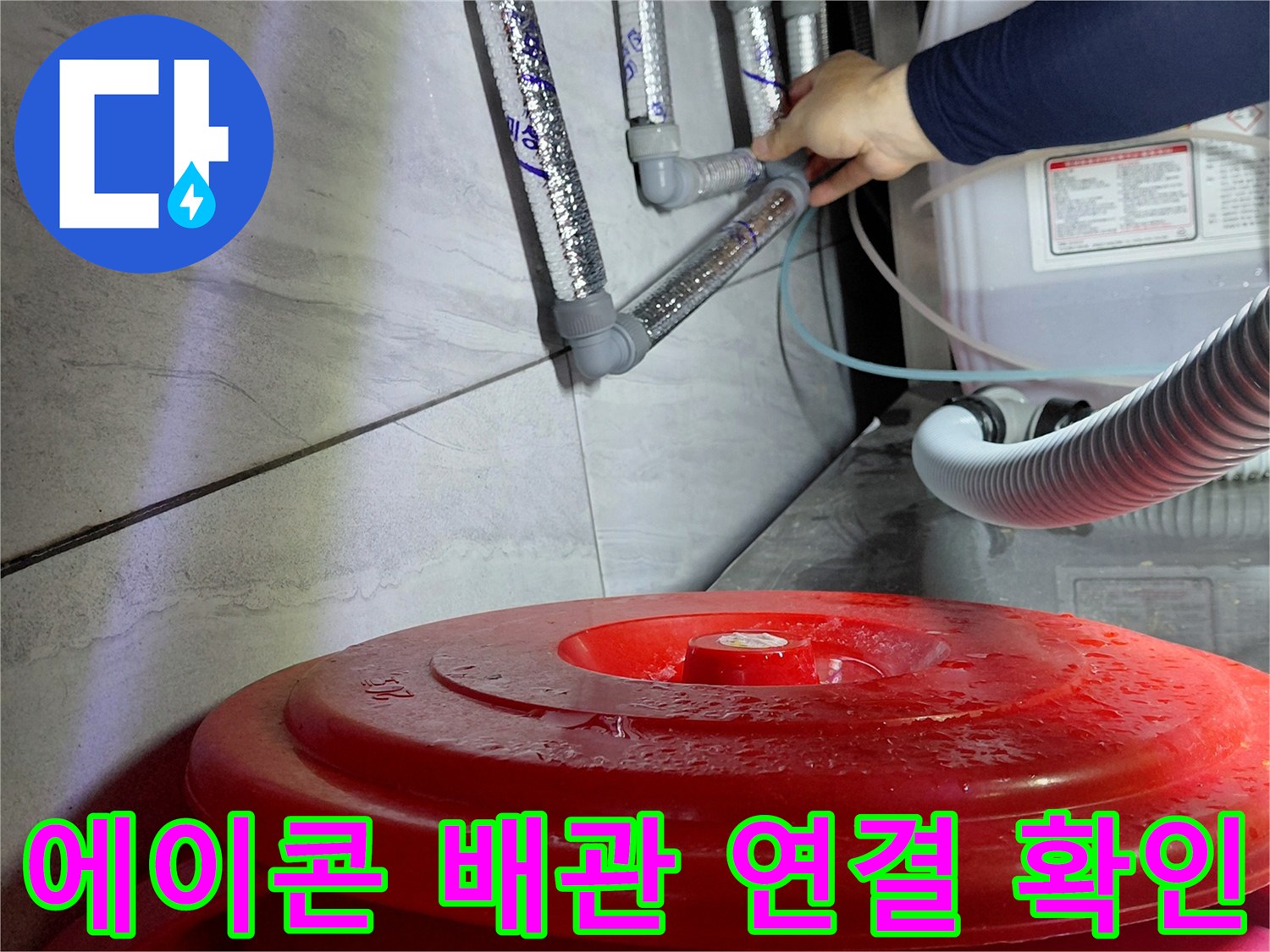 싱크대 밑 공간의 은색 금속 부속과 회색 에이콘 배관 모습