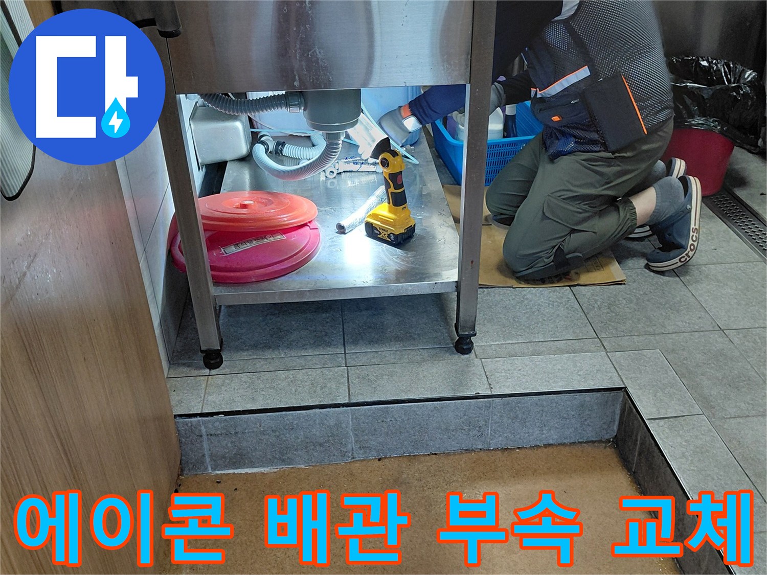싱크대 하부장 내부-전동 드릴을 사용하여 배관 연결부를 정밀하게 수선하는 과정