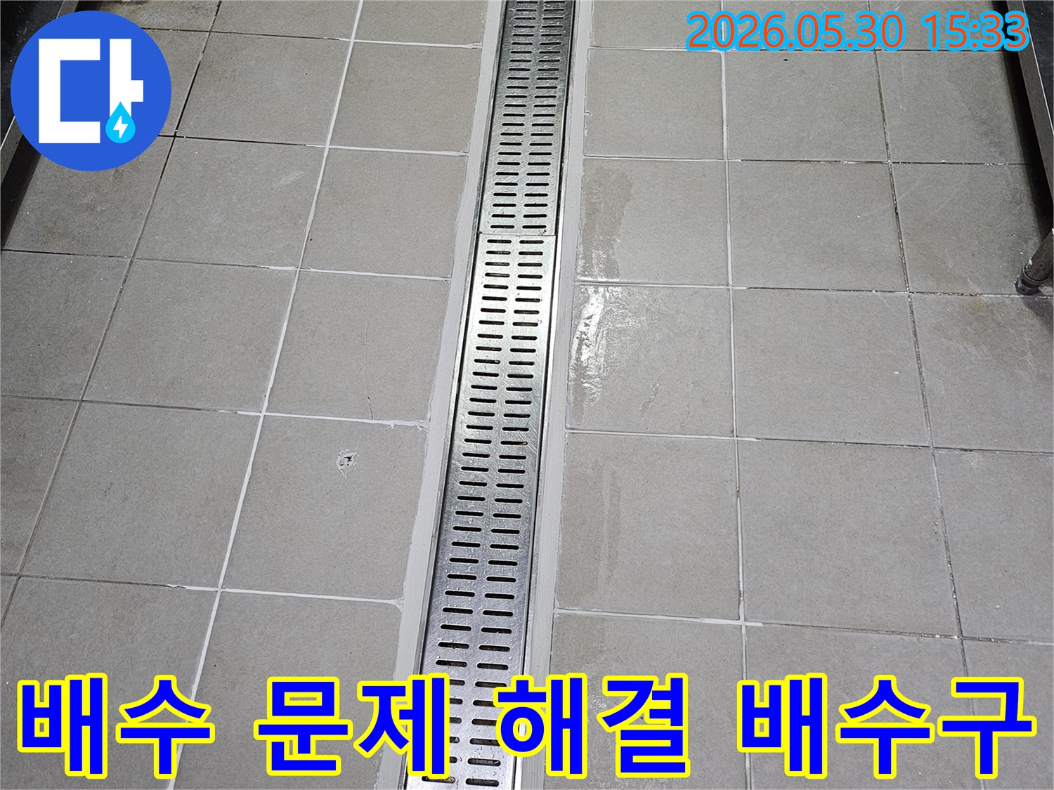 타일 벽면에-새롭게 설치된-스테인리스 선형 배수구-물이 고이지 않고-빠르게 배수되도록-시공된 모습