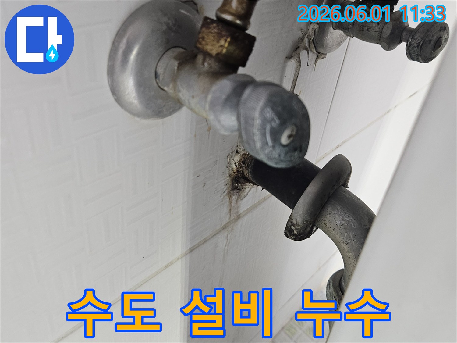욕실 벽에 설치된 수도 설비의 밸브 주변에서-발생한 물샘과 부식 현장을 촬영한 이미지입니다.