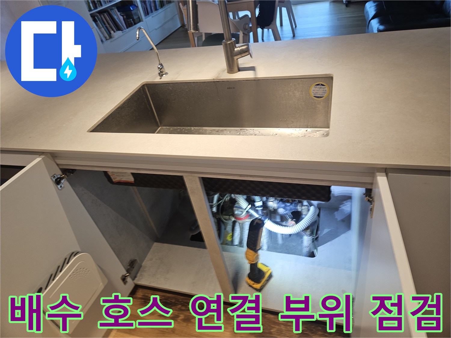 싱크대 하부 구조물 사이로 보이는-배관과 전동 공구