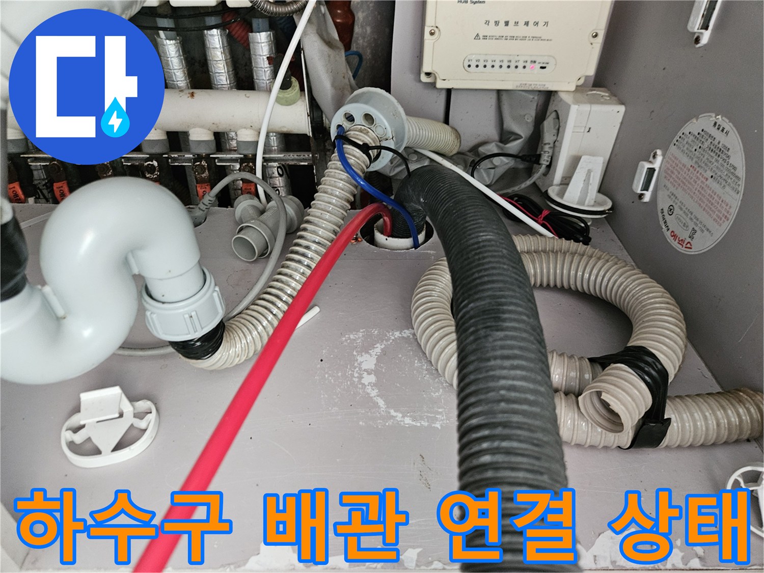 싱크대 아래쪽 복잡하게 얽힌 하수 배관 및 호스 모습
