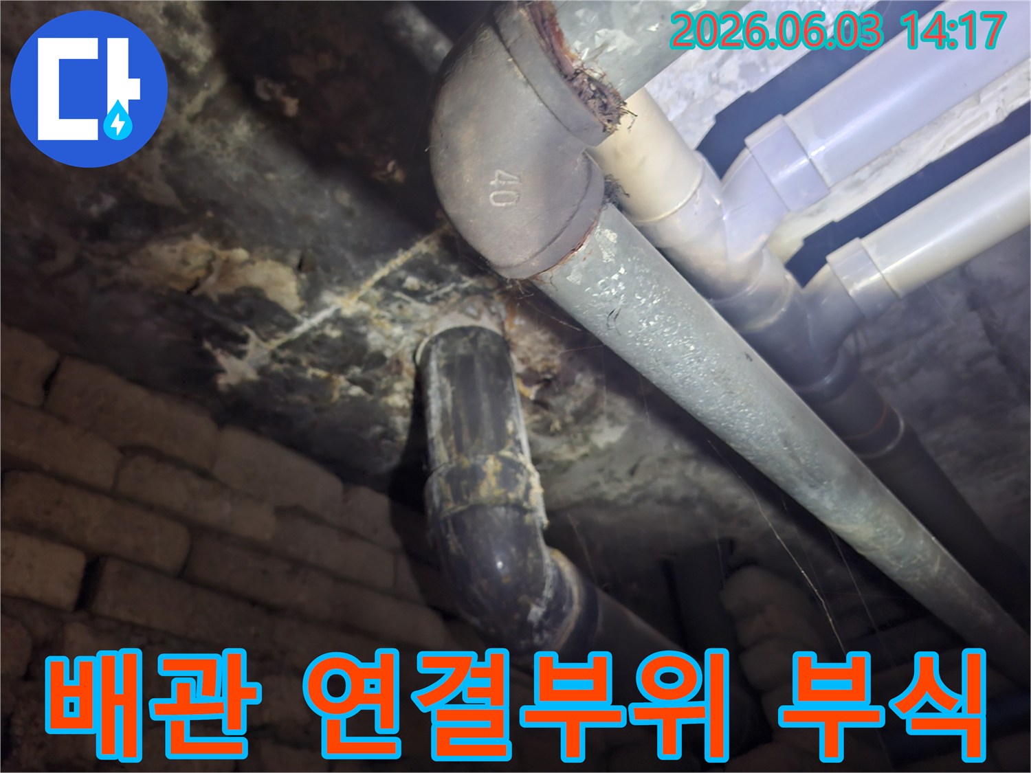 아파트 지하 배관의 연결부위에서-심각하게 진행된 부식 상태를-전문가가 면밀히 점검하는 모습