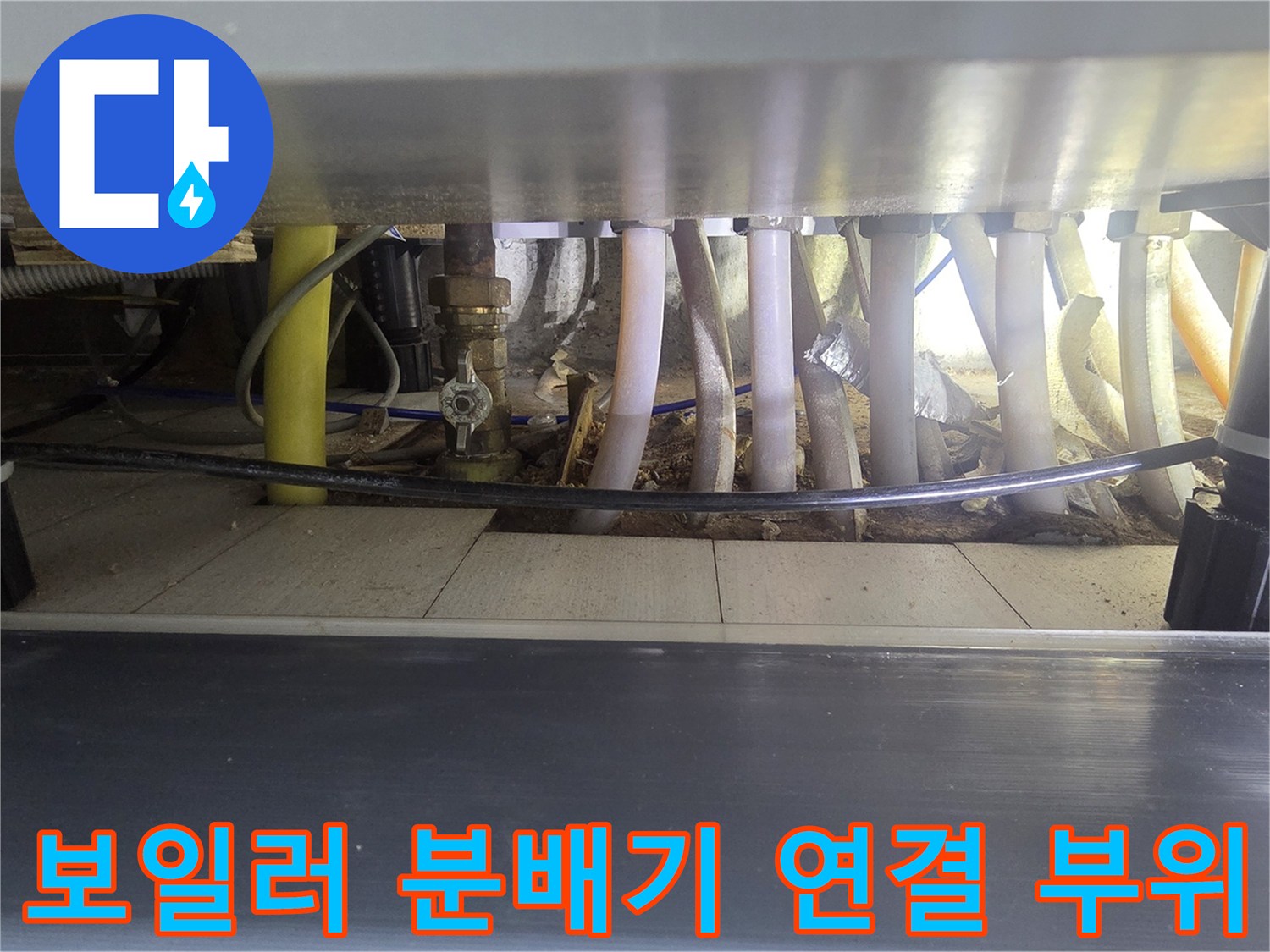 싱크대 아래 보일러 분배기와 밸브 및 배관들이 연결된 장면