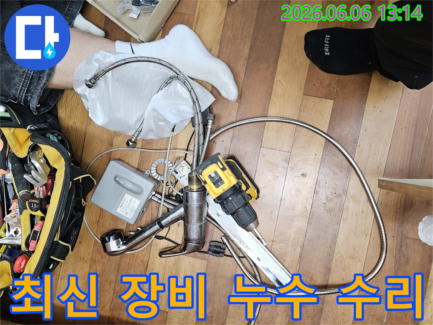 수도꼭지 교체 작업을 위한-새로운 수전과-연결 호스-그리고 전동 공구가 바닥에 펼쳐진 현장입니다.