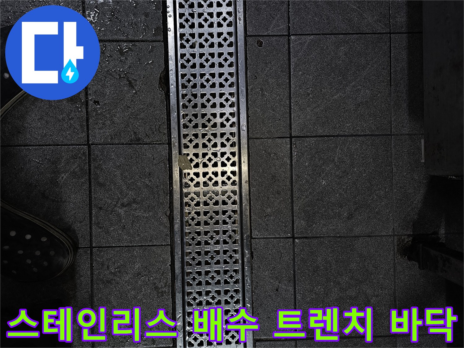 물기가 스며든 상가 매장의 스테인리스 배수구와 어두운 타일