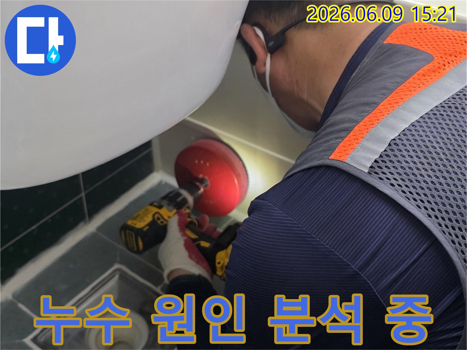 안전-조끼를-입은-전문가가-욕실-배수구-근처의-누수-지점을-정확히-파악하기-위해-전동-공구를-사용하여-작업하는-장면