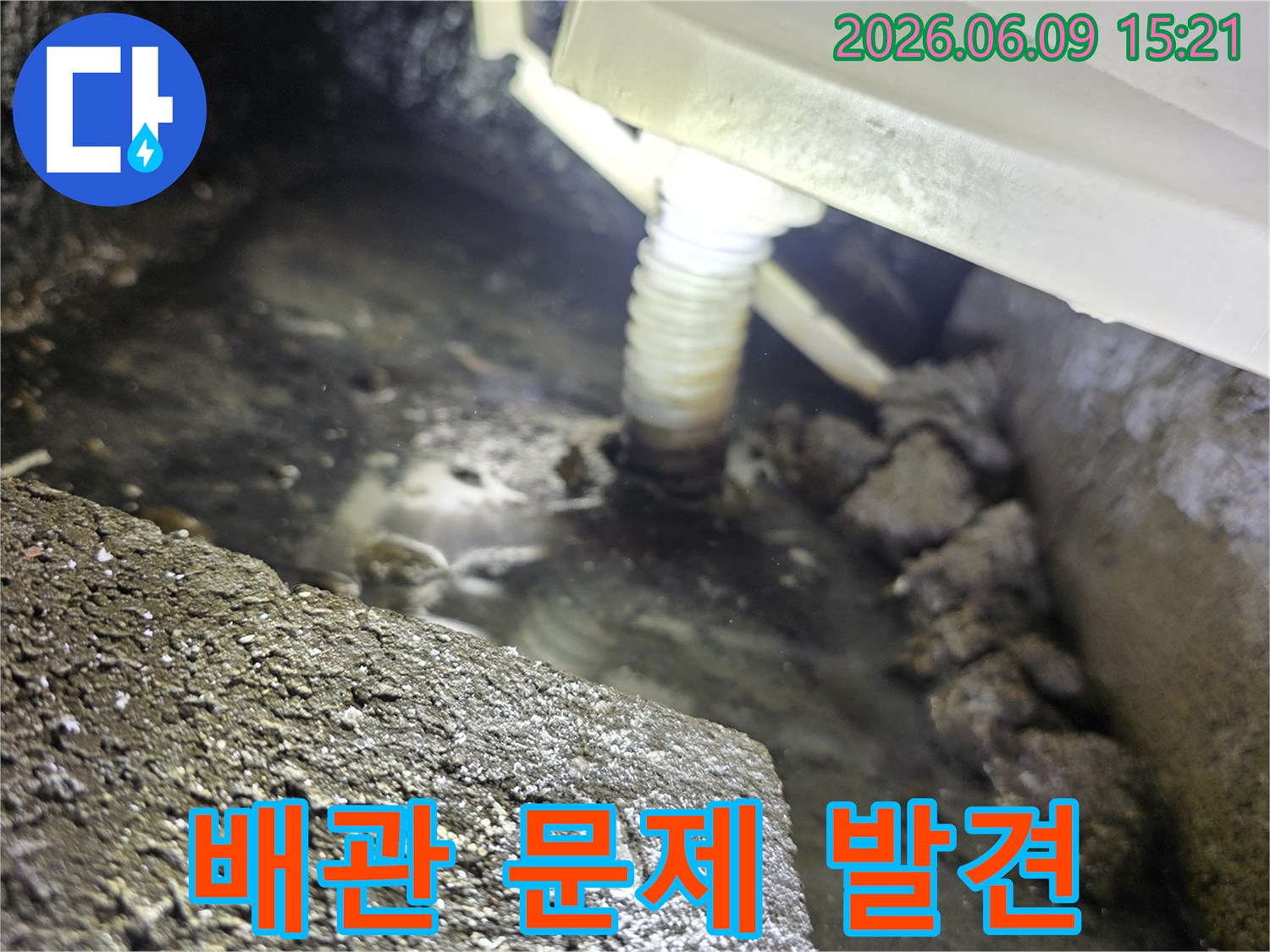 어두운 곳에서-플래시로 비춘-배관 하부의-고인 물과-누수 흔적