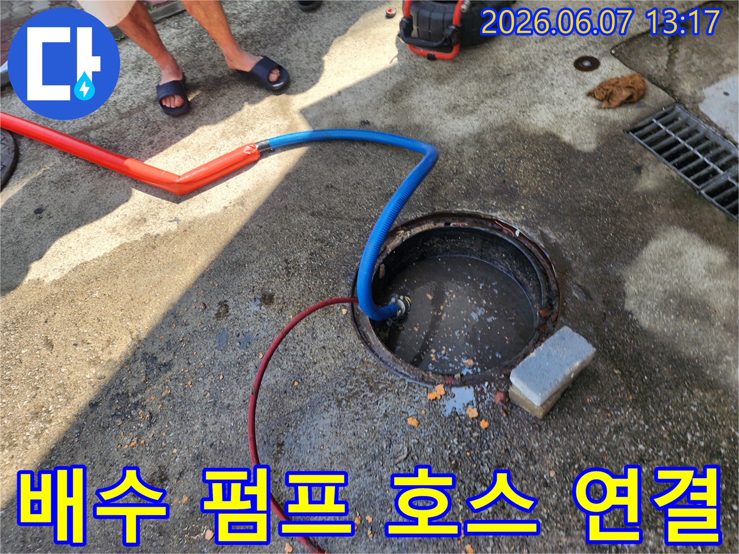 파란색 배수 호스가 오수받이 안쪽으로 깊숙이 들어간 현장 사진입니다.
