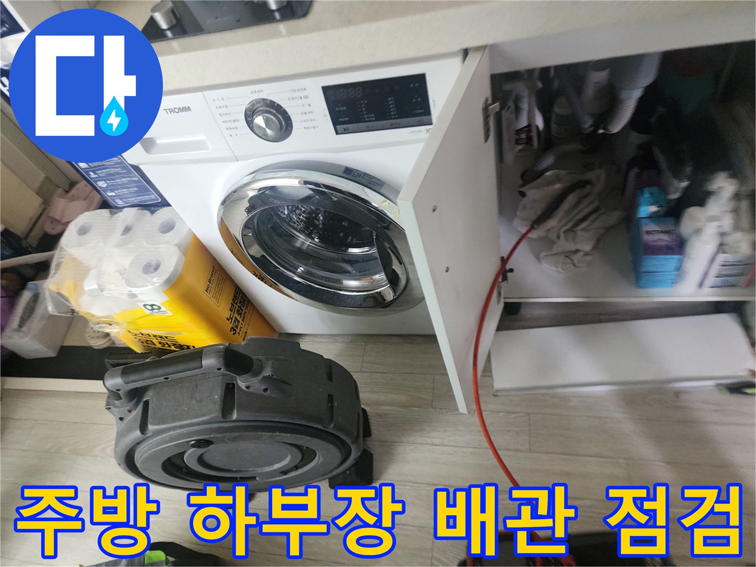싱크대 아래 수납장 공간에서 진행되는 배관 상태 확인 작업