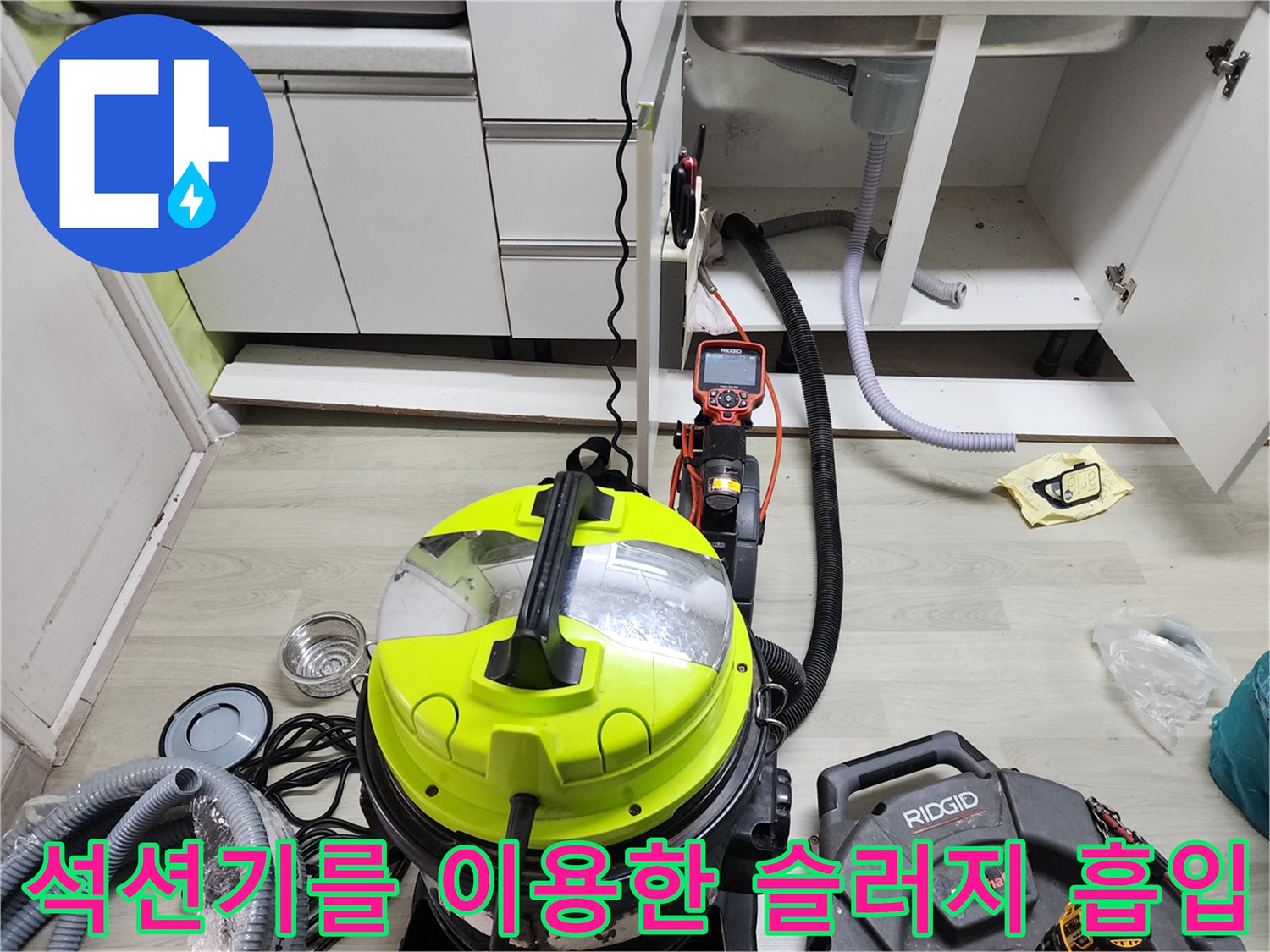 싱크대 밑 하수관 부근에서 석션 호스를 이용하여 이물질을 뽑아내는 모습