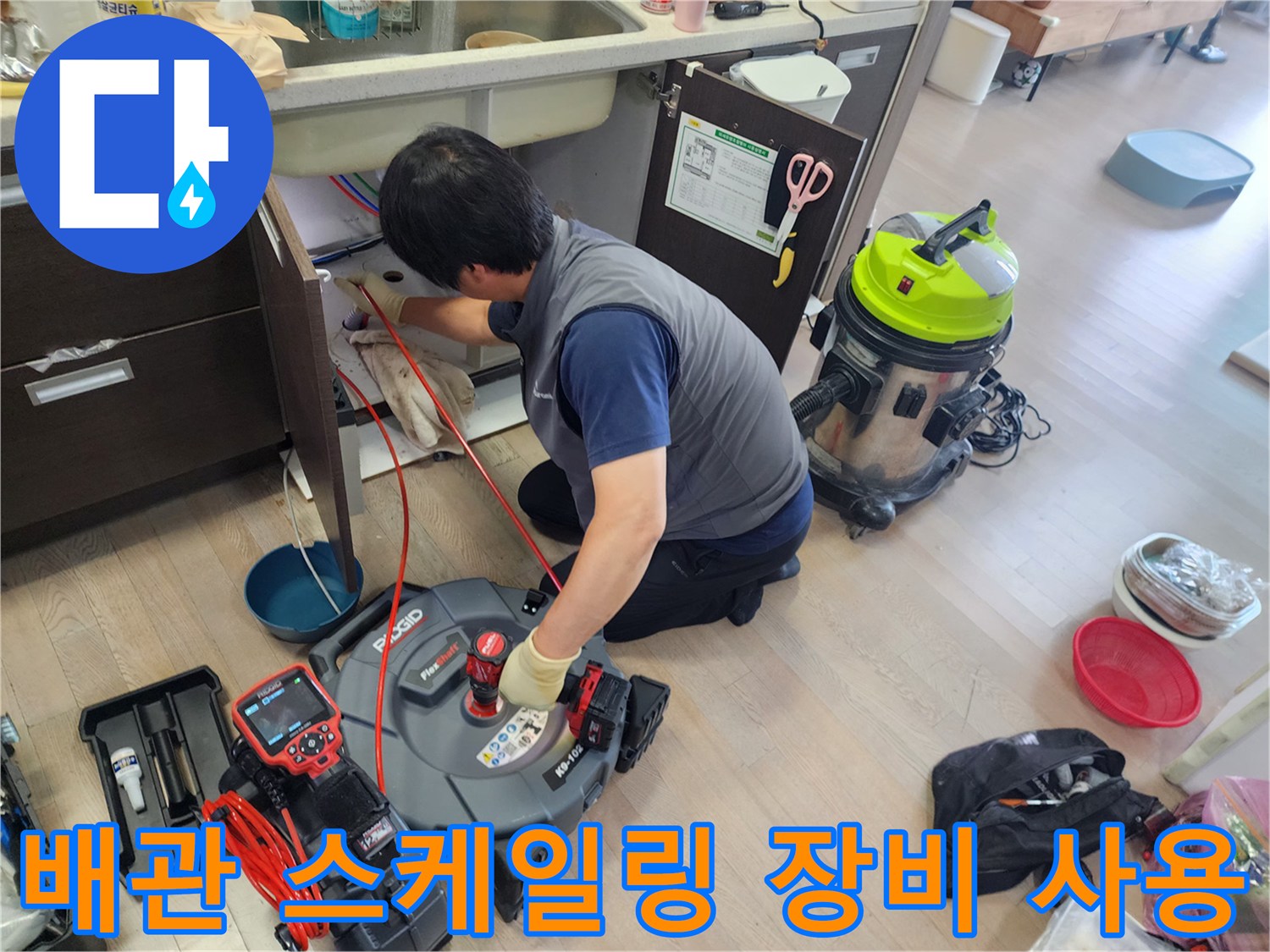 싱크대 아래 공간에서 회전하는 노즐로 배관 내부를 청소하는 엔지니어의 작업 모습