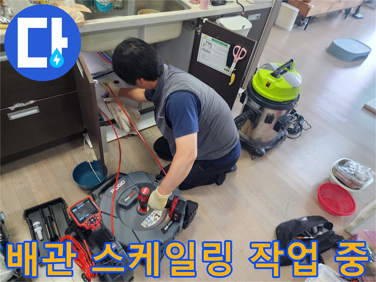 엔지니어가 싱크대 하단에서 전문 장비로 배관 내부 슬러지를 제거하는 모습