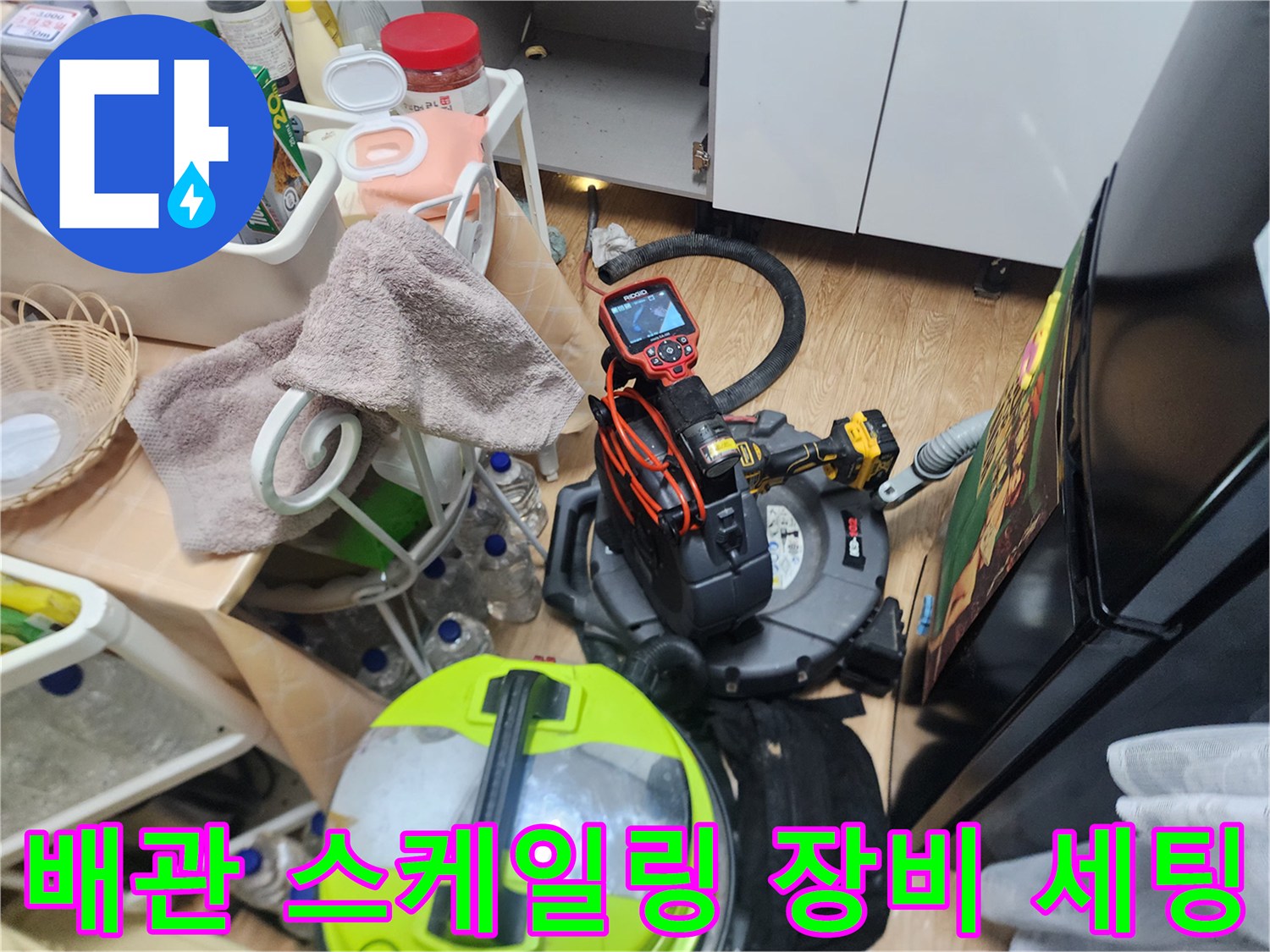 싱크대 아래 좁은 공간에 배치된 배관 청소용 석션기와 카메라