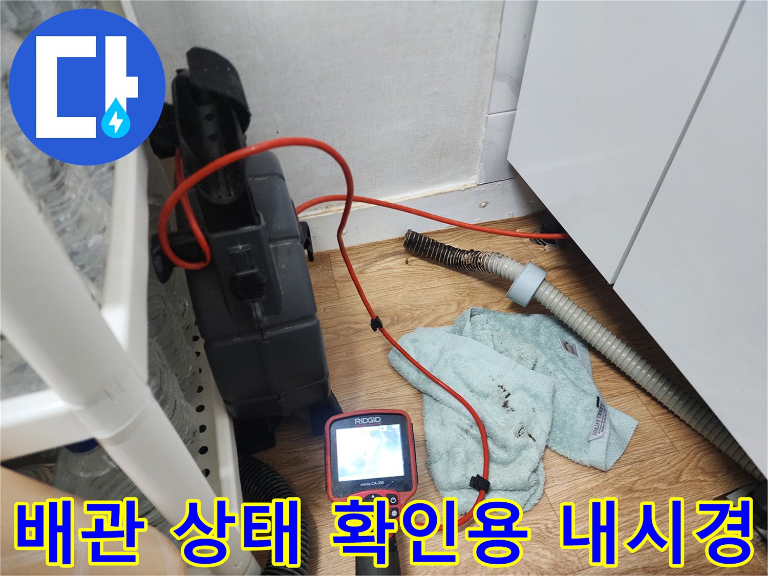 싱크대 하부장 아래 배치된 내시경 모니터와 배관 작업용 장비들
