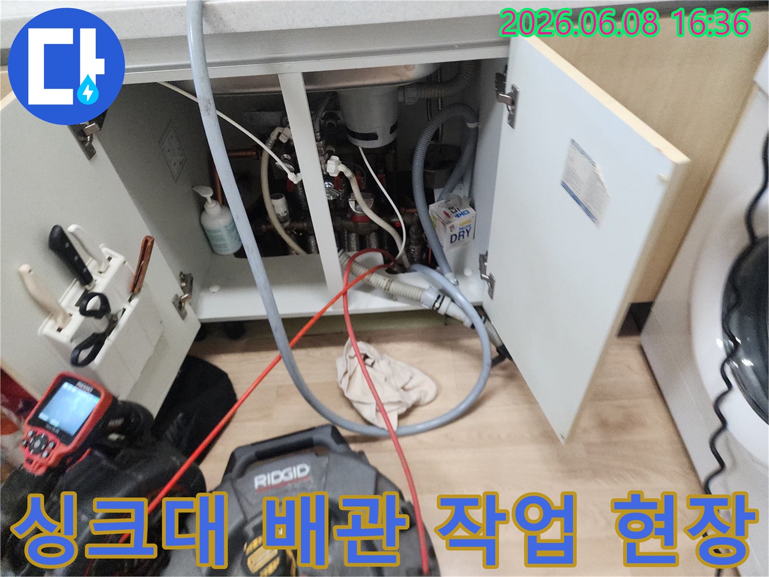 싱크대 아래쪽 배관과 연결된 장비가 놓여있는 작업 모습입니다.