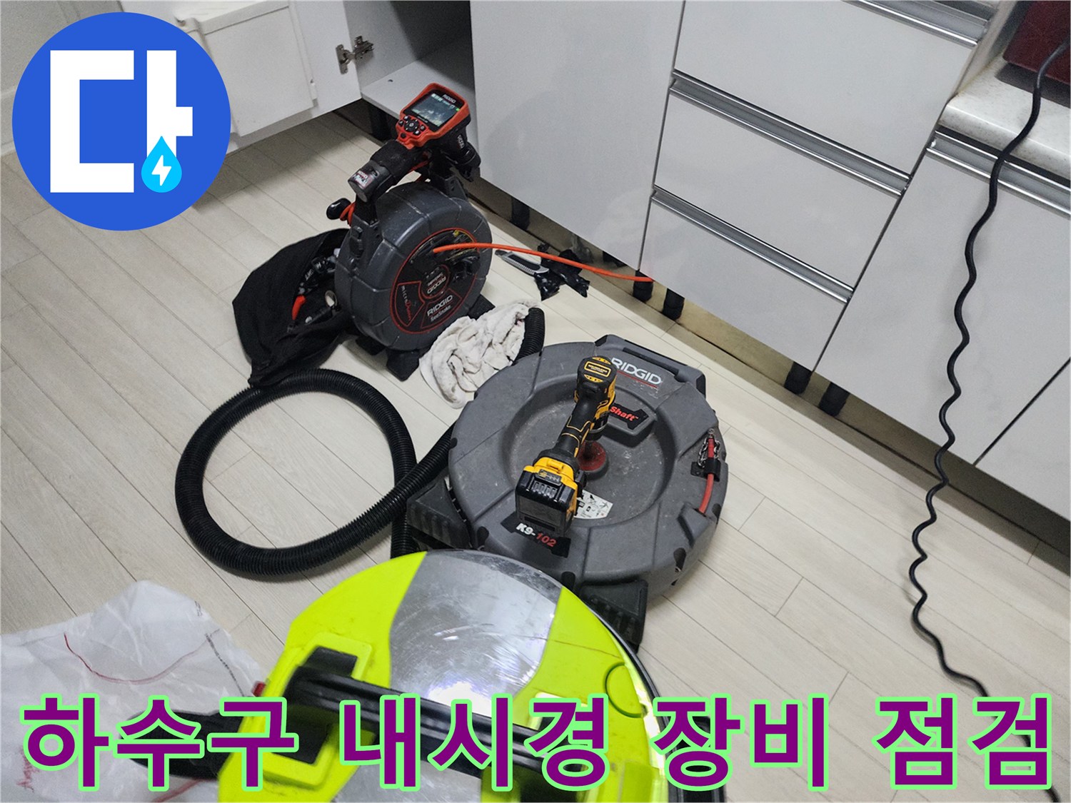 바닥에 배치된 배관 내시락 릴과 전동 공구 및 작업용 수건