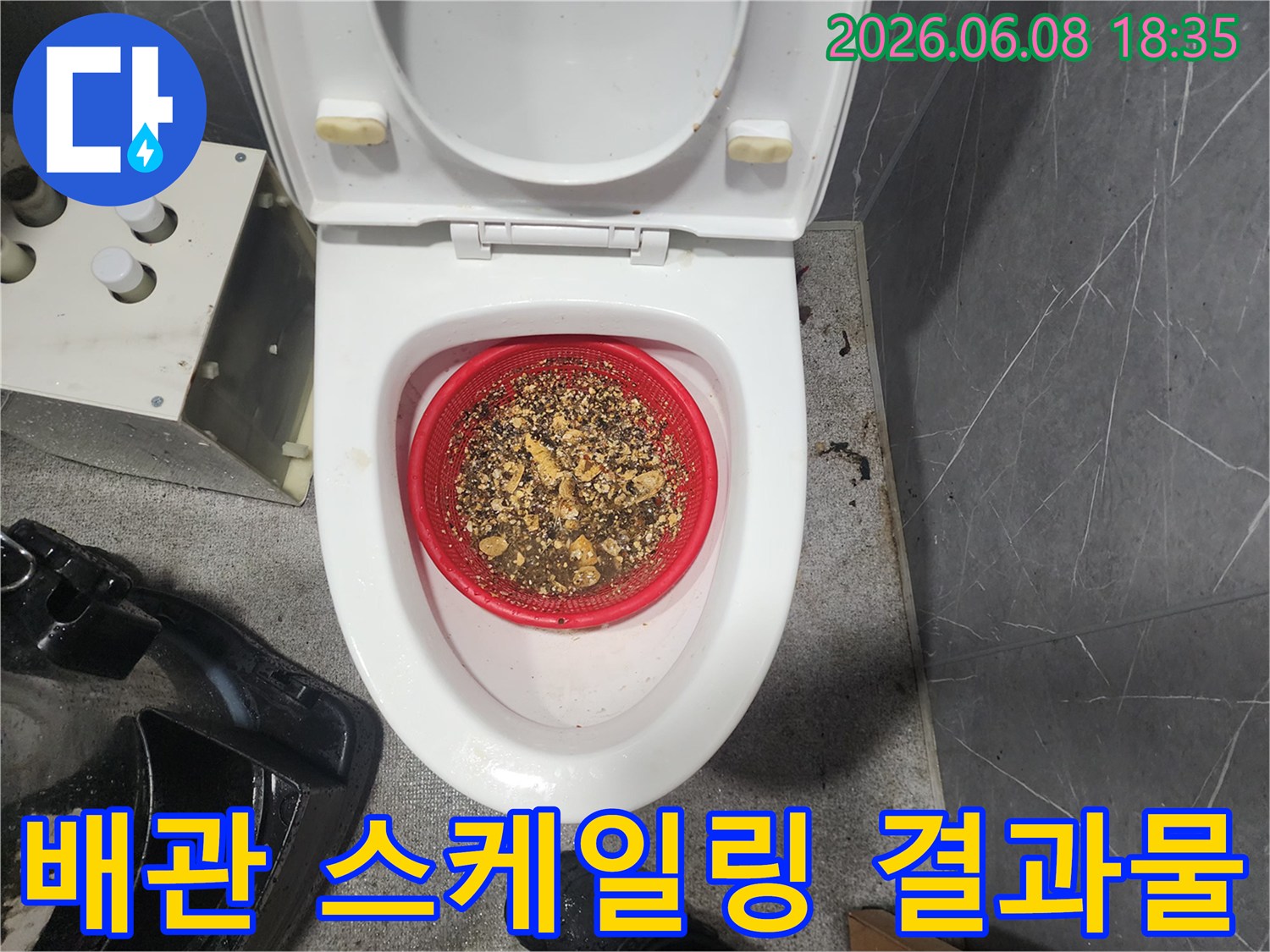 빨간색 체에 걸러진 배관 속 굳은 슬러지 조각들