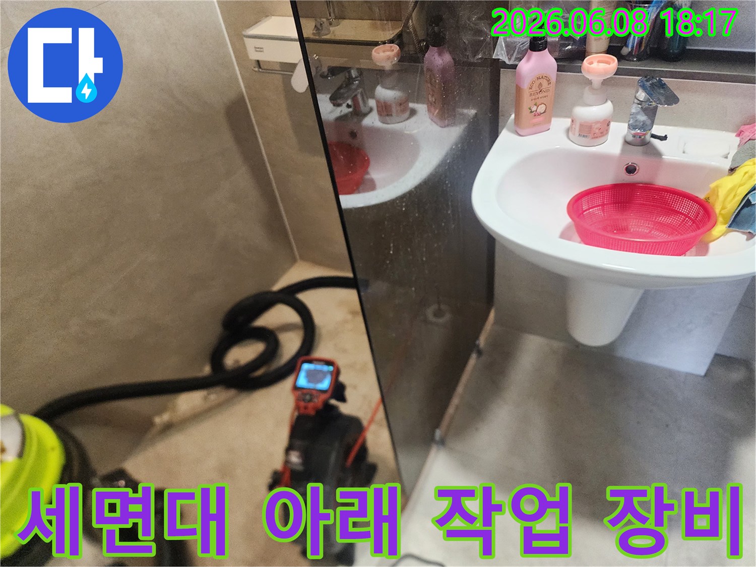 세면대 하부 배관 작업을 위해 설치된 내시경 모니터와 석션 호스 뭉치