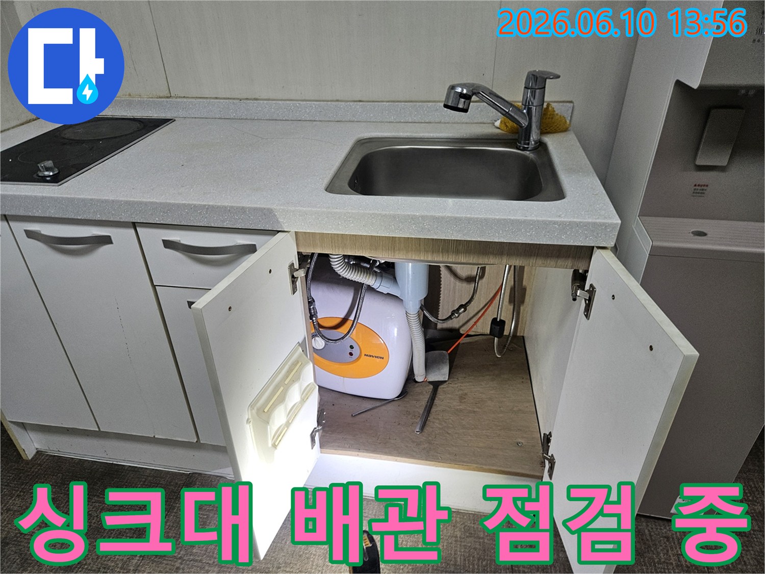싱크대 밑 물고임의 원인을 찾기 위해-배관과 온수기를-세밀하게 점검하고 있습니다.