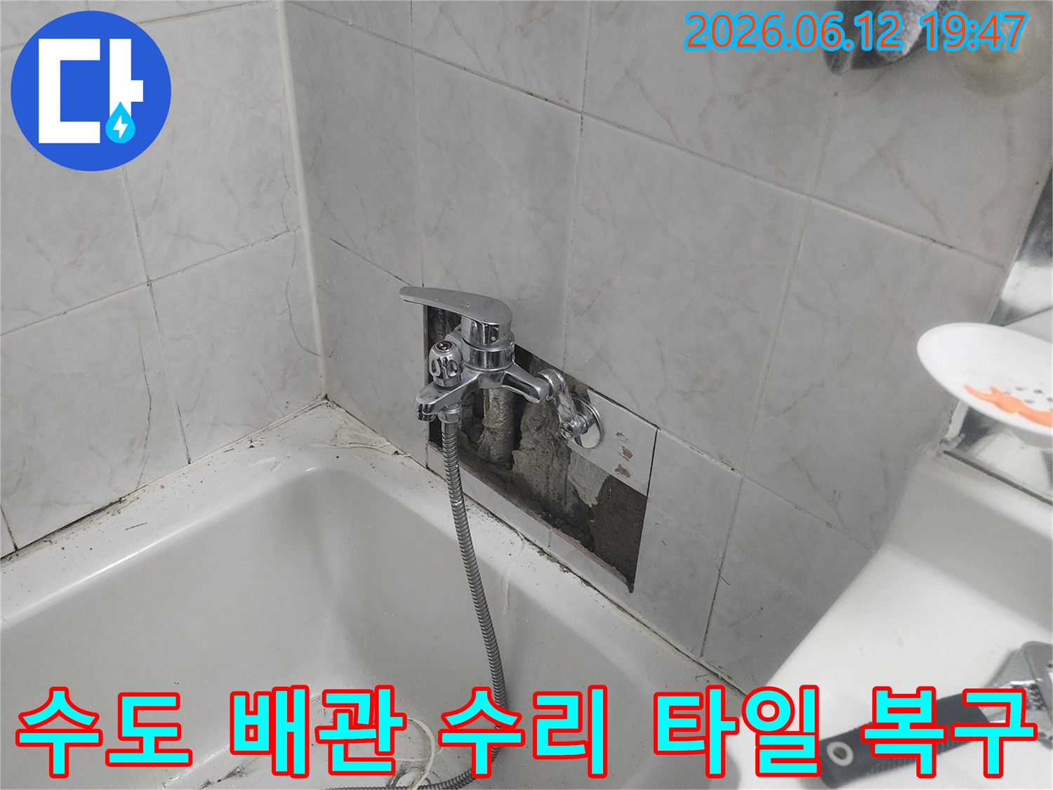 욕실 벽면의 타일이 제거된-상태에서-누수된 수도 배관을-수리하고-새로운 수전을-설치하며-타일 복구 작업이-진행되는-모습을-담은-사진입니다.
