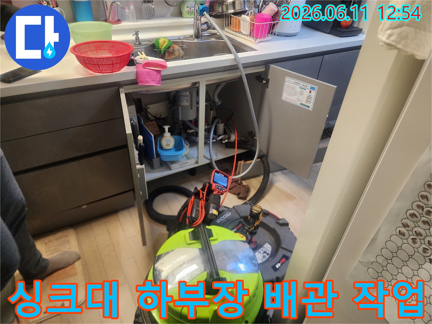 의정부 호원동 싱크대 하부장 내부에서 진행 중인 배관 스케일링 장비와 석션기 모습