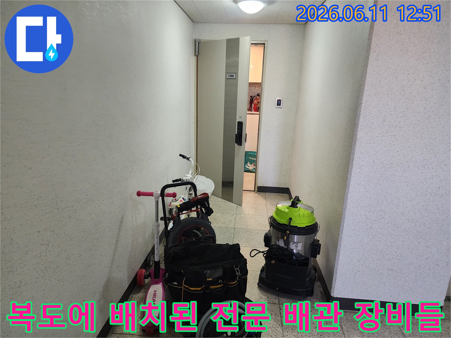 작업을 위해 복도 통로에 나란히 놓인 배관 청소용 진공기와 작업 도구 가방입니다.