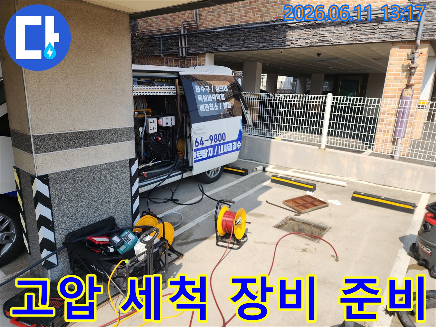 작업 현장 맨홀 옆에 놓인 고압 세척기와 호스 릴