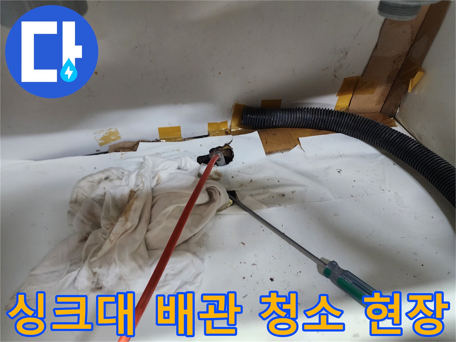 싱크대 아래쪽 배관 입구와 작업용 도구가 놓인 모습