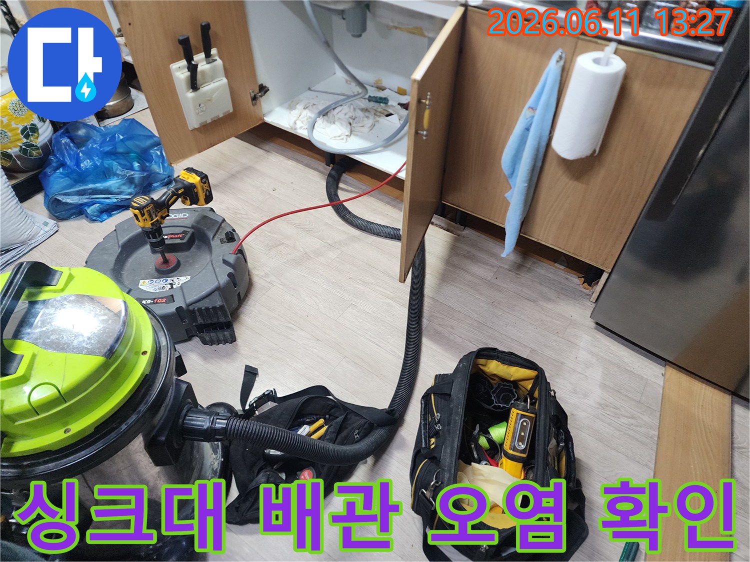 싱크대 하부장 내부의-오염된 배수관과 청소용 석션 장비 모습입니다.